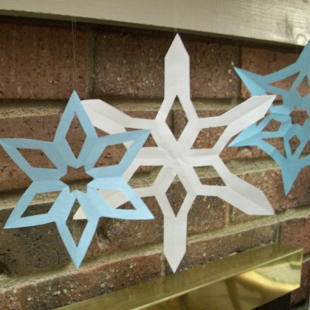 Snowflakes hanging from fireplace mantel.
